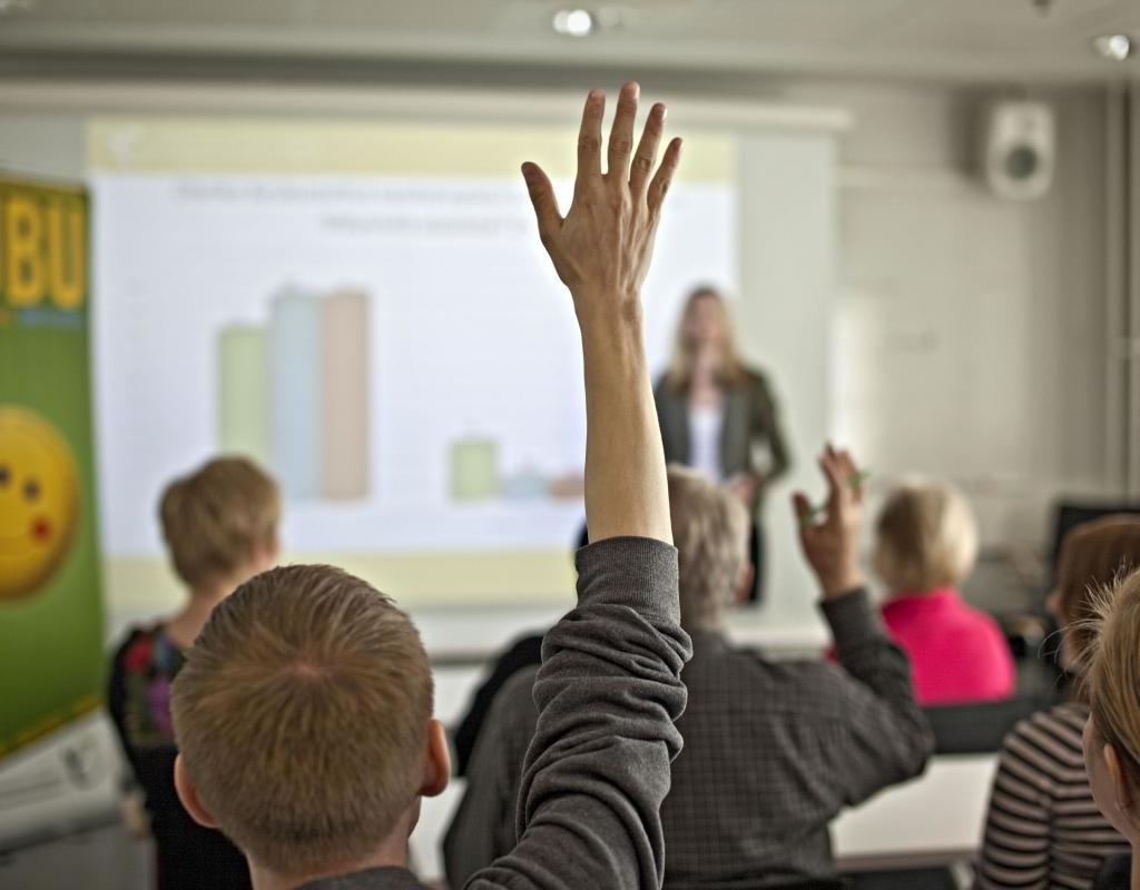 A person raising a hand in a class room.