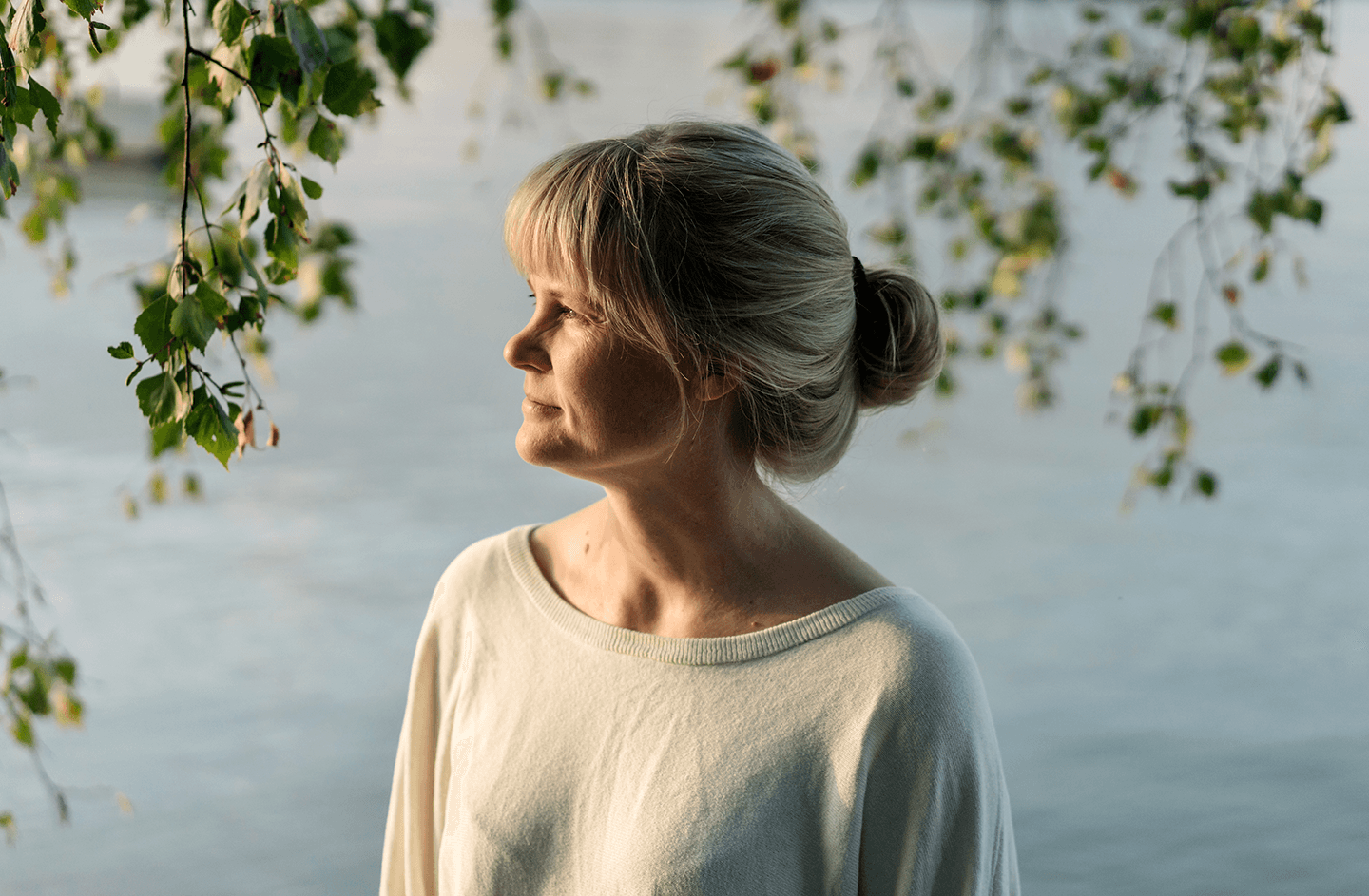 En kvinna står utanför vid vattnet.