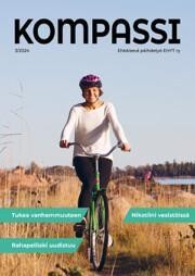 Kompassi-lehden kansi. Polkupyöräilijä ajamassa heinikkoisella rannalla.